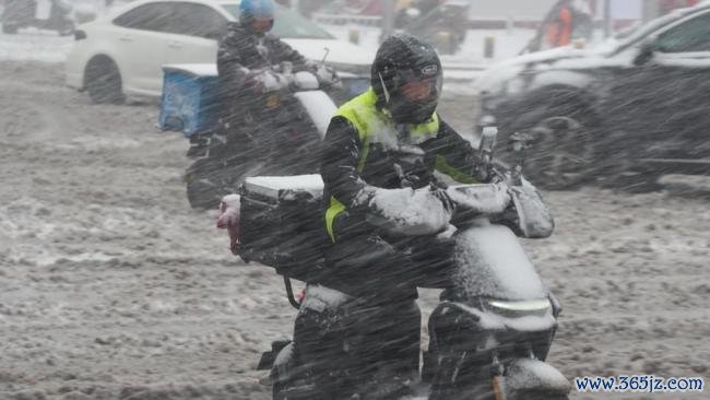 外卖小哥暴雪中自便前行送餐 湿滑路面艰巨骑行